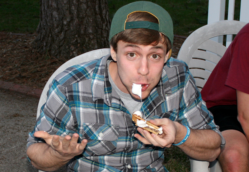 Eating a sticky S'more at college student cookout